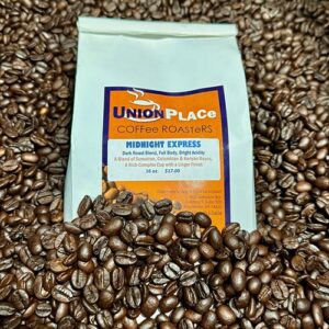 A bag of Union Place Coffee Roasters Midnight Express dark roasted coffee surrounded by dark roasted beans