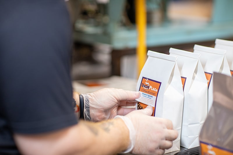 An employee at Union Place Coffee Roasters packaging bags of coffee beans